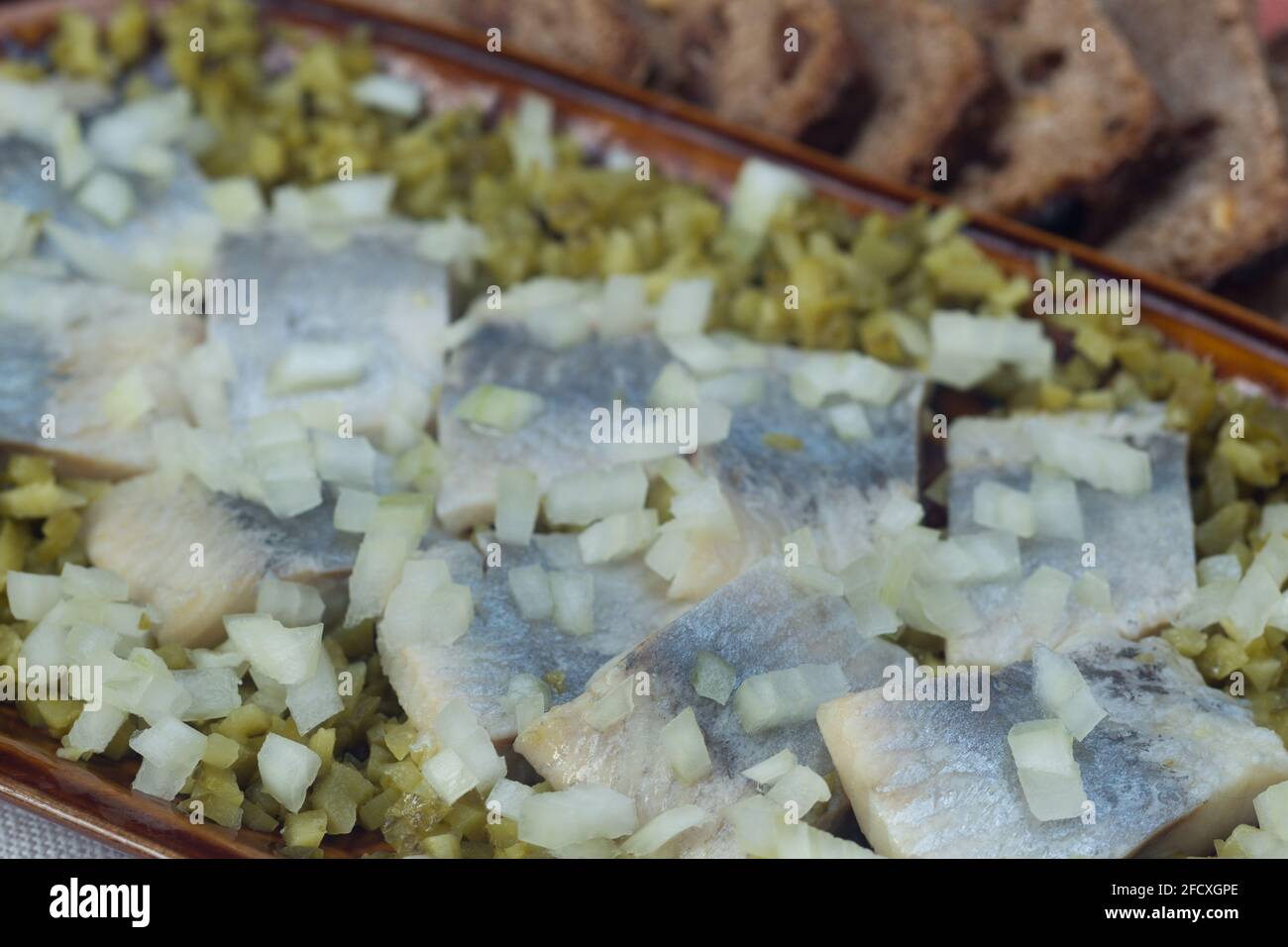 Hering mit Zwiebel und eingelegter Gurke auf dem Teller Nahaufnahme selektiv Fokus Stockfoto
