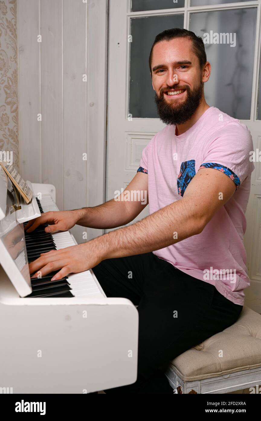 Ein junger, lässig gekleideter Mann spielt Klavier. Stockfoto