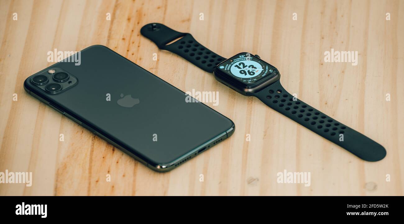 Apple iPhone 11 pro max und Apple Watch Series 6 liegen flach auf einem Holztisch, Luxus- und Lifestyle-Konzept. Stockfoto