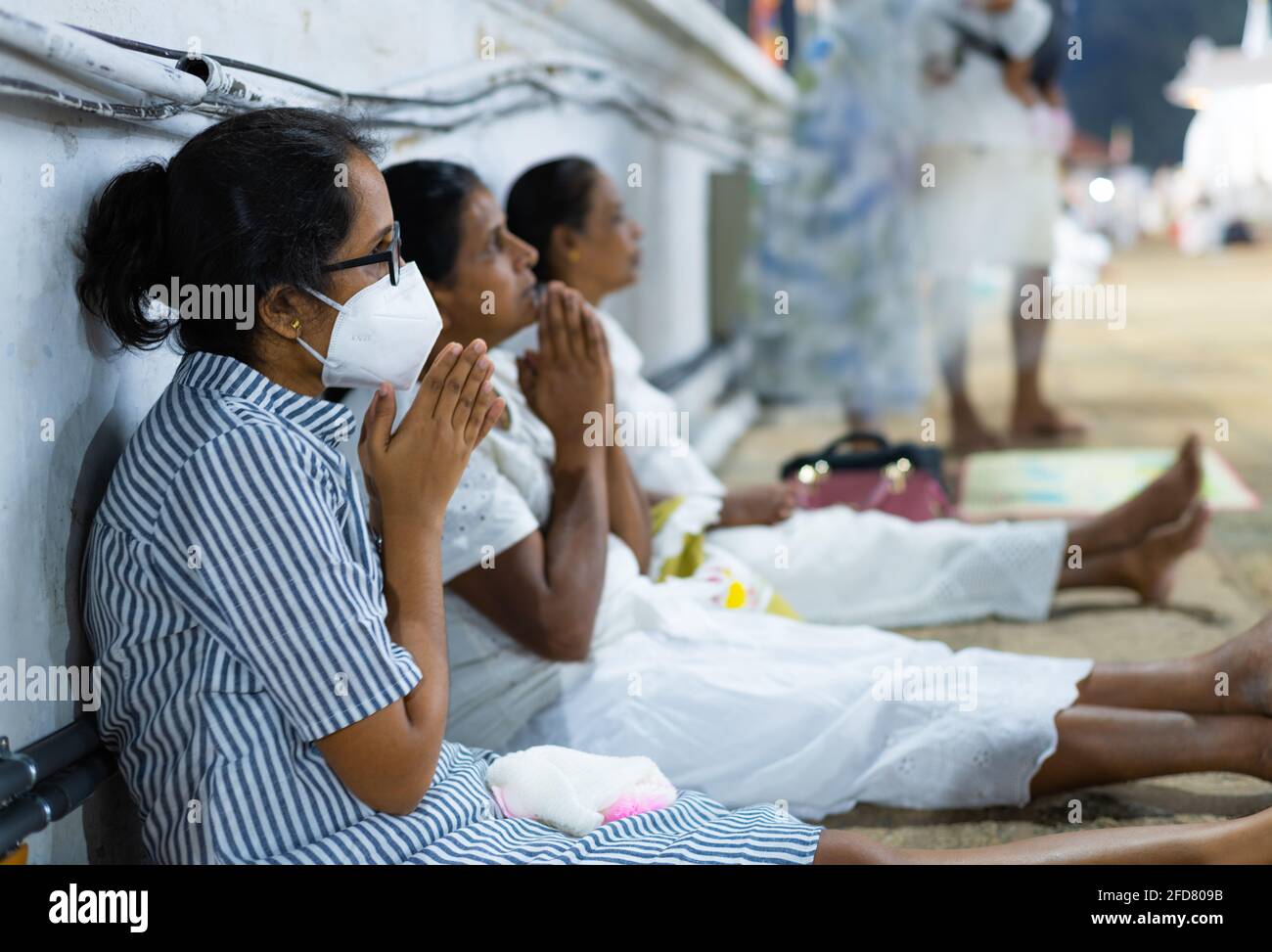 Anuradhapura, Sri Lanka - 03 30 2021: Buddhistische Anhänger beten im Ruwanwelimahasaya und tragen eine schützende Gesichtsmaske, während sie in der Nacht anbeten Stockfoto