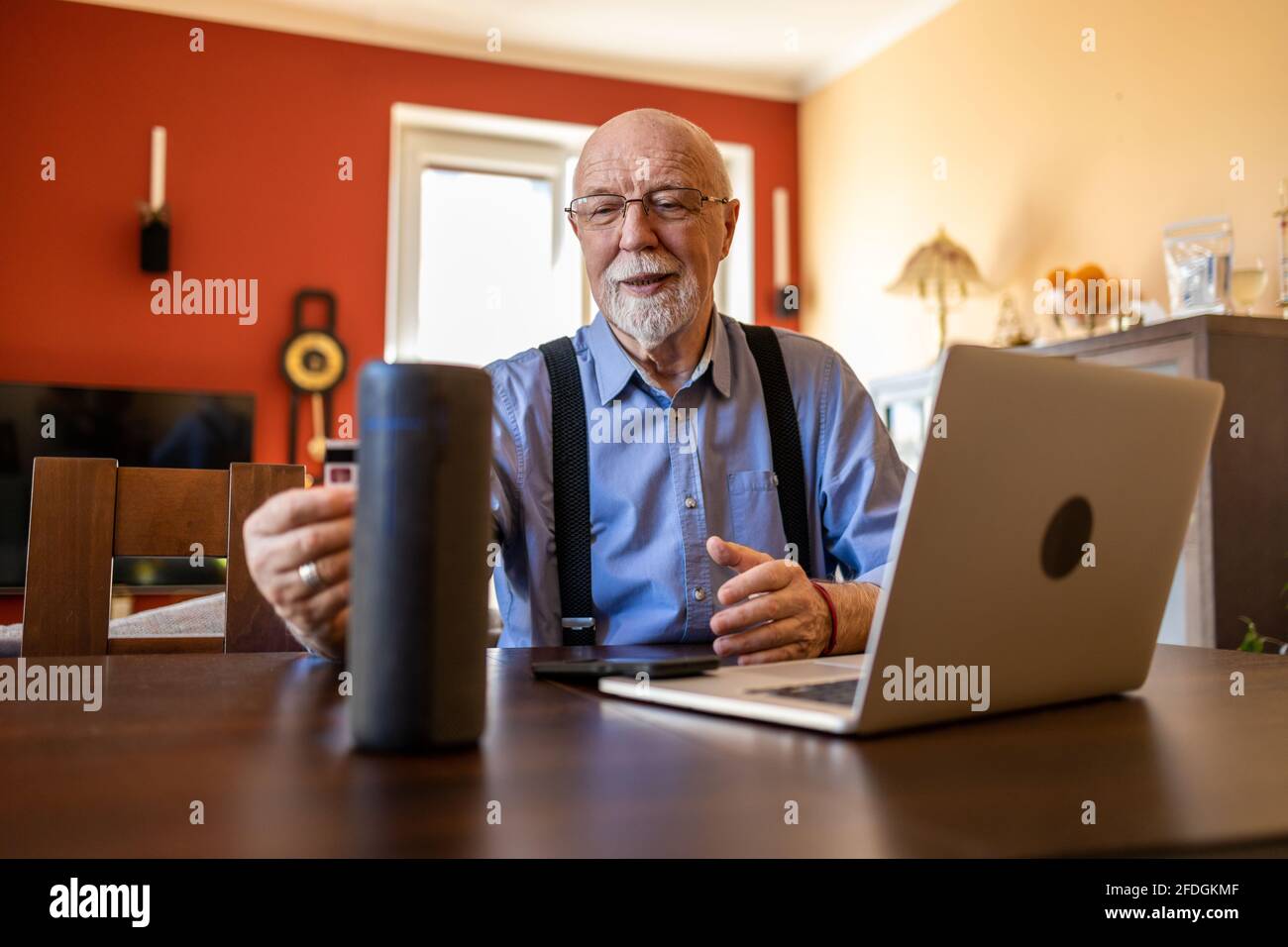 Älterer Mann, der zu Hause den virtuellen Assistenten verwendet Stockfoto