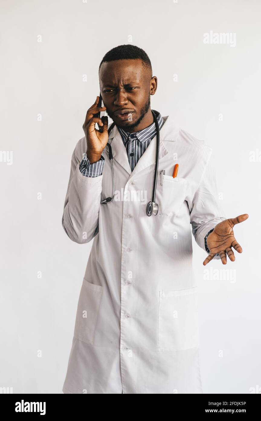 Ein afroamerikanischer schwarzer junger Arzt in einem weißen Mantel spricht am Telefon. Isoliert Stockfoto