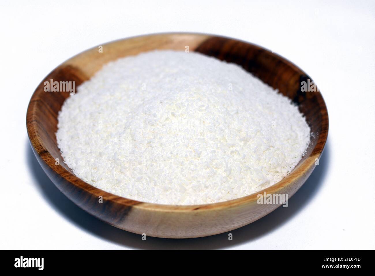 Geriebene Kokosnuss in einer braunen Holzschüssel, frische Kokosspäne auf weißem Hintergrund isoliert Stockfoto