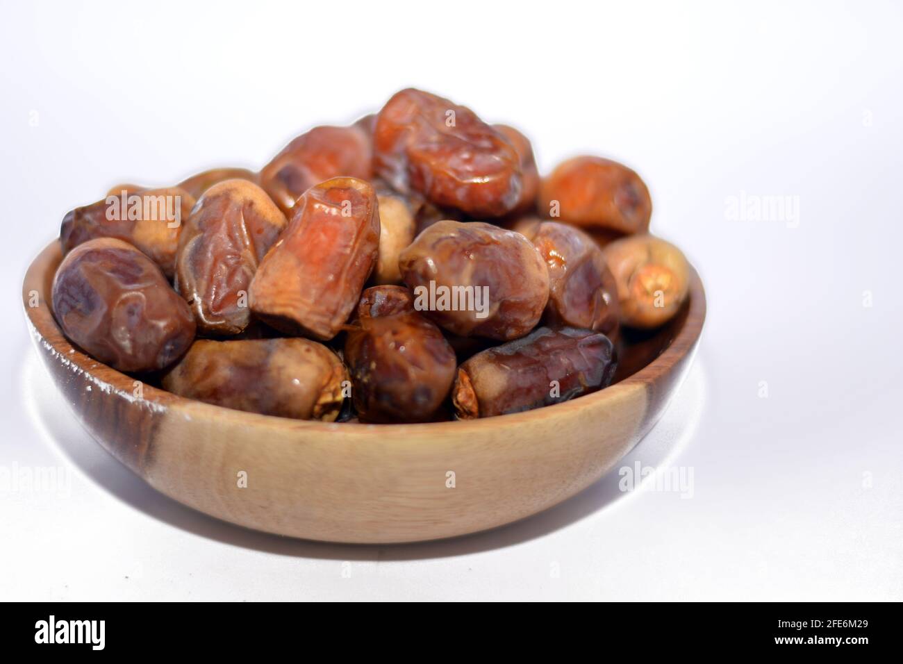 Getrocknete Datteln, Früchte in einer Holzschüssel, isoliert auf weißem Hintergrund, getrocknete Datteln, die im Ramadan-Monat zum Frühstück als erste iftar-Mahlzeit verwendet wurden Stockfoto