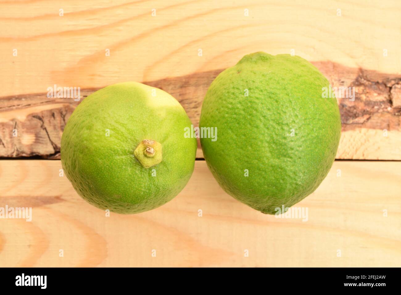 Zwei leuchtend grüne reife Limetten, auf einem Holztisch. Stockfoto