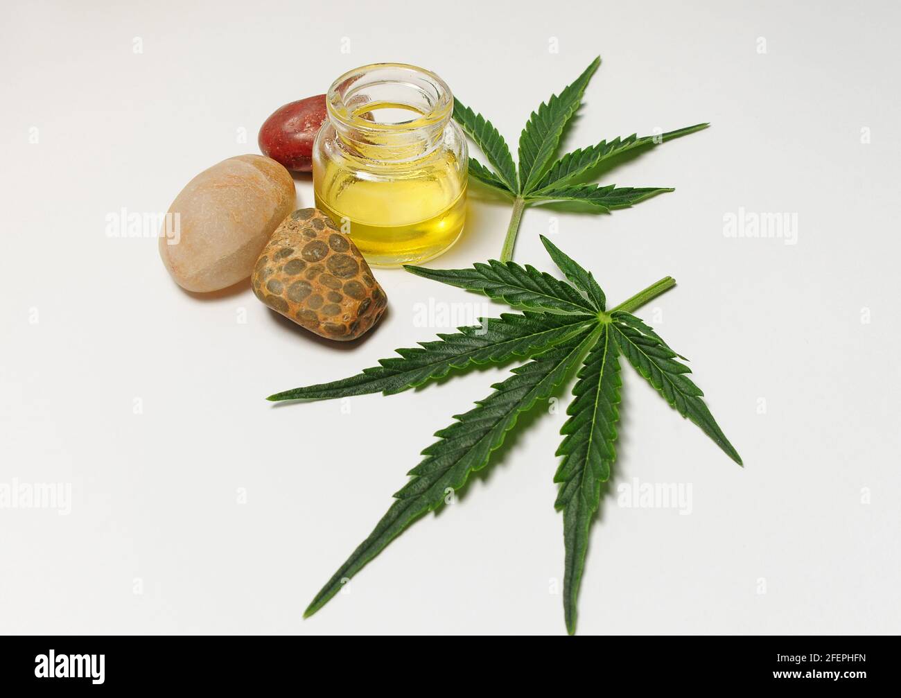 Marihuanablätter, cbd-Öl, Seestones, Spa-Erholung. Frische Cannabisblätter aus der Nähe, isoliert auf weißem Hintergrund. Entspannung zu Hause, Zeitvertreib-Therapie. Stockfoto