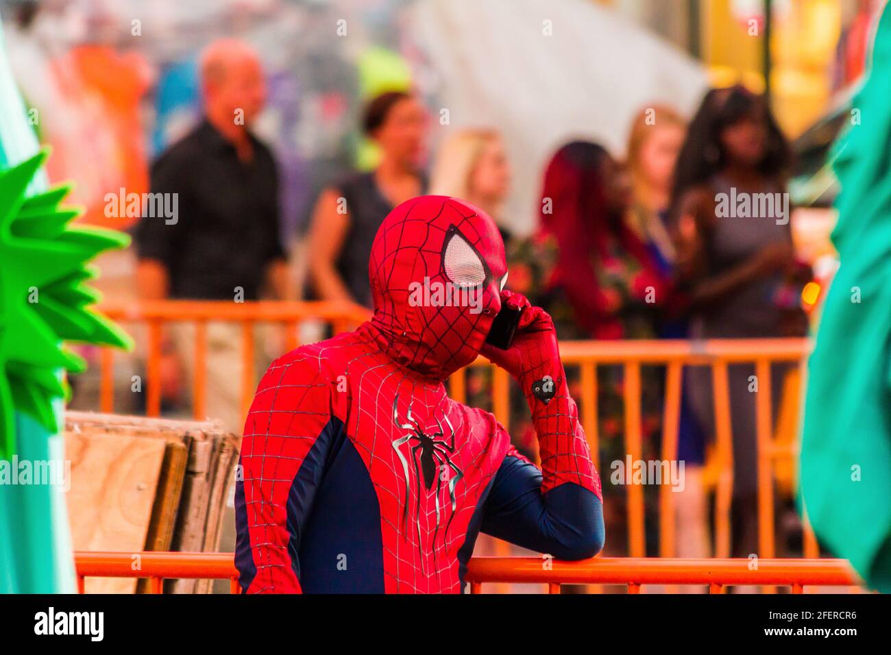 Nahaufnahme eines Mannes in einem Spiderman-Kostüm, der spricht Am Telefon am Times Square und die Leute im Hintergrund Stockfoto