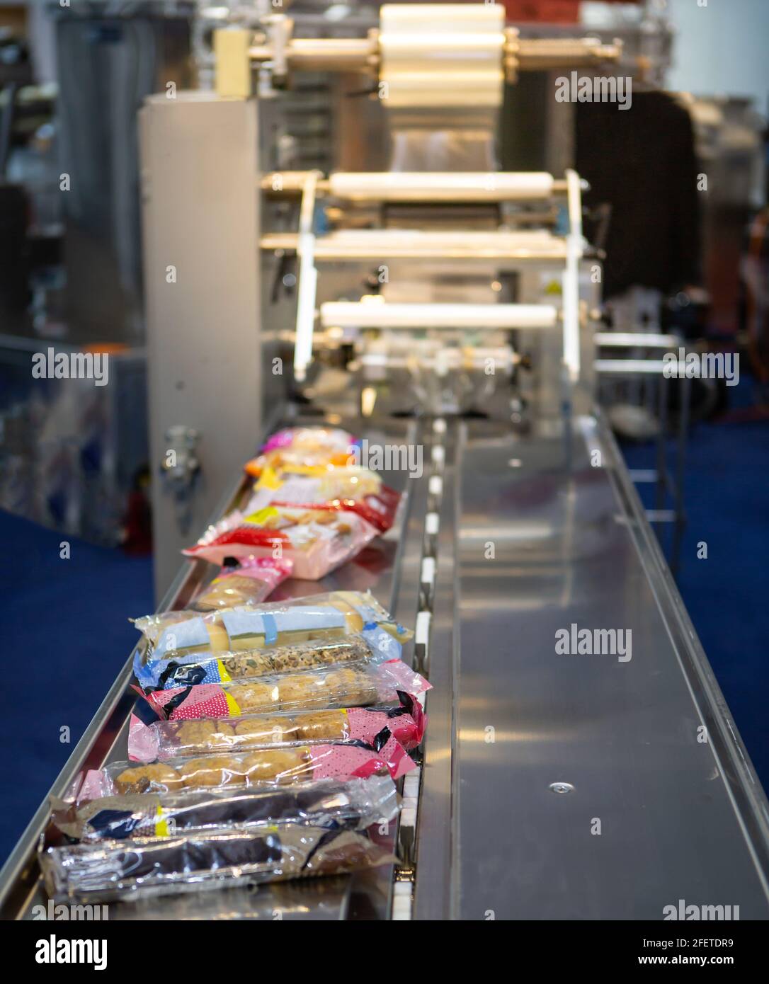 Automatisches Verpacken der Kissenverpackungsmaschine für Bäckereiprodukte. Brot, Toast, Brötchen Kunststoff-Verpackungsmaschine auf Bäckerei Produktionslinie Stockfoto