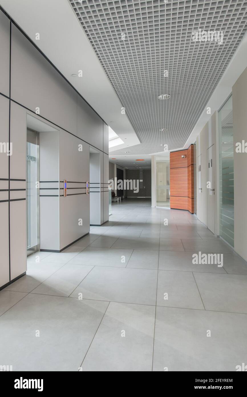 Leerer Korridor des Business Centers mit Bodenfliesen und parallelen Linien an der Wand, eine Mischung aus minimalistischen Designs Stockfoto