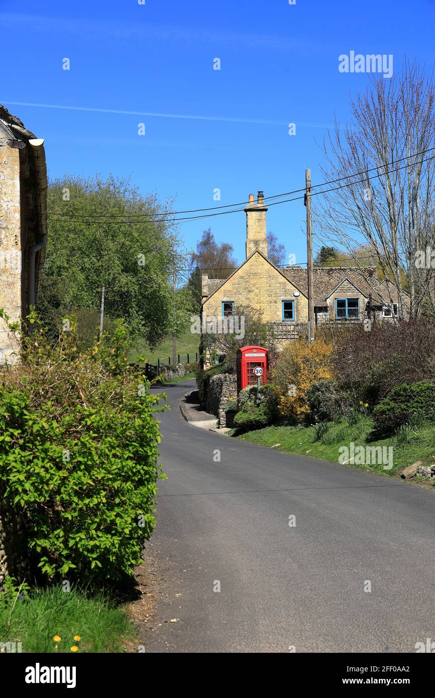 Die hübschen Dorfhäuser von Compton Abdale in den Cotswolds Mit einer traditionellen roten Telefonbox Stockfoto