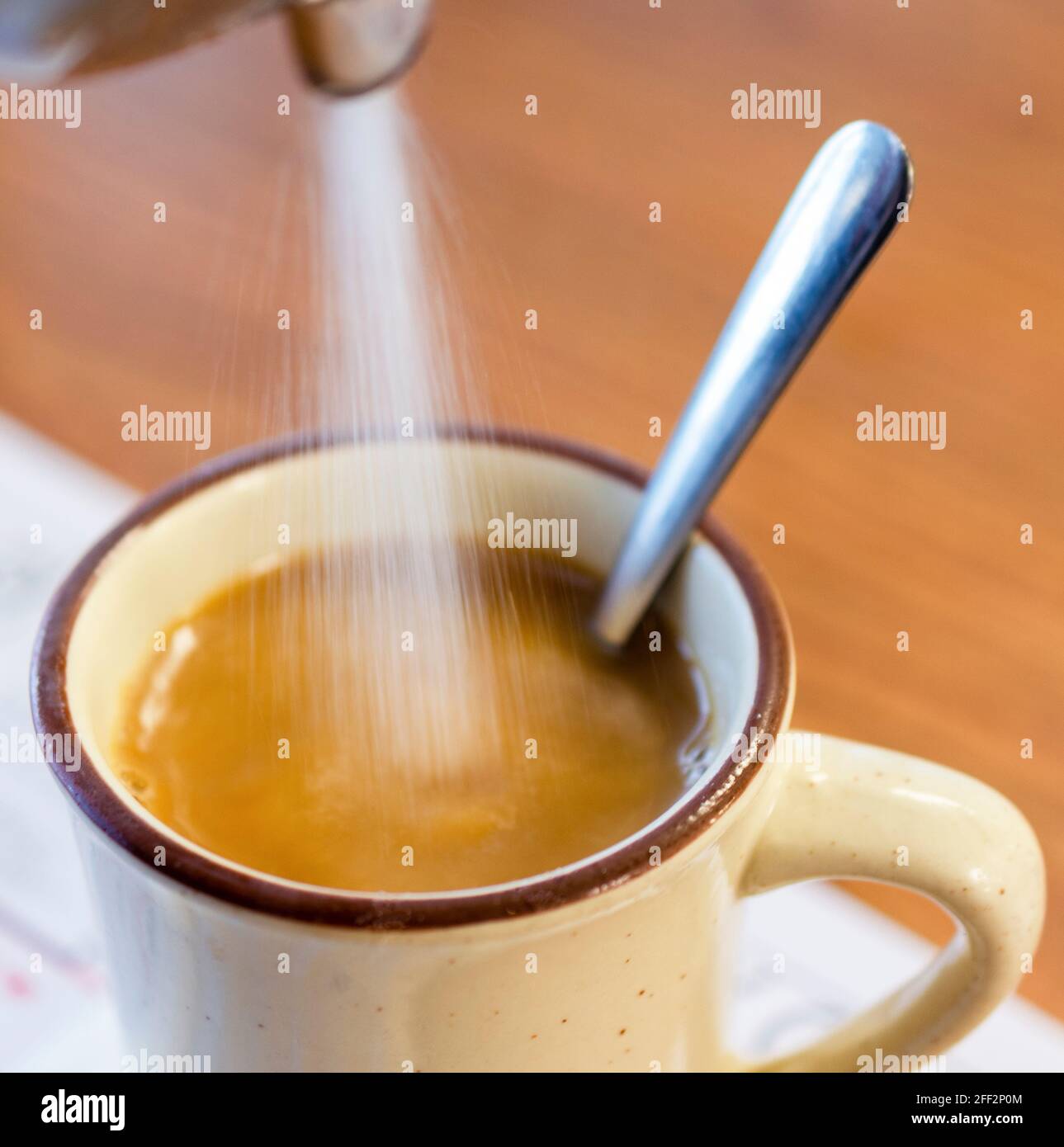 Zucker wird morgens aus einem Zuckerspender in eine heiße Tasse Kaffee in  einem Diner gegossen. Der Griff des Löffels ragt aus dem Becher  Stockfotografie - Alamy
