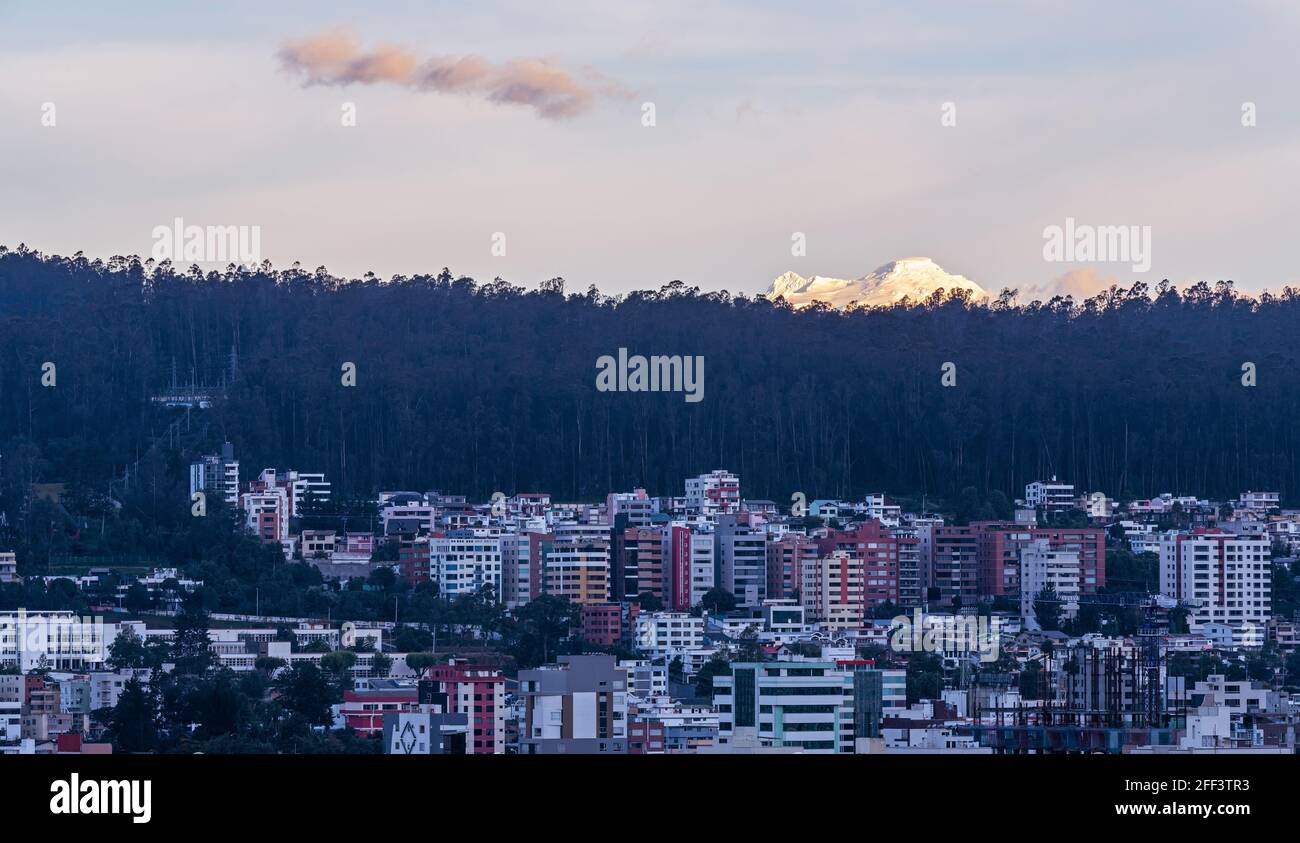 Quito Stadtbild-Panorama bei Sonnenuntergang mit Mehrfamilienhäusern und Antisana Vulkan, Ecuador. Stockfoto