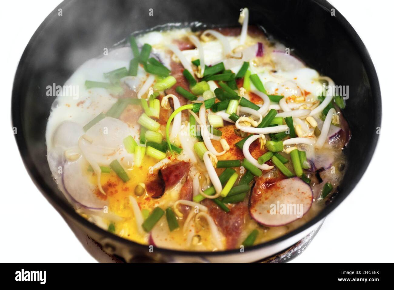 Vegetarisches Omelett mit Ei und frischem Gemüse in einer Pfanne mit Rauch zubereiten, isoliert auf weißem Hintergrund. Stockfoto