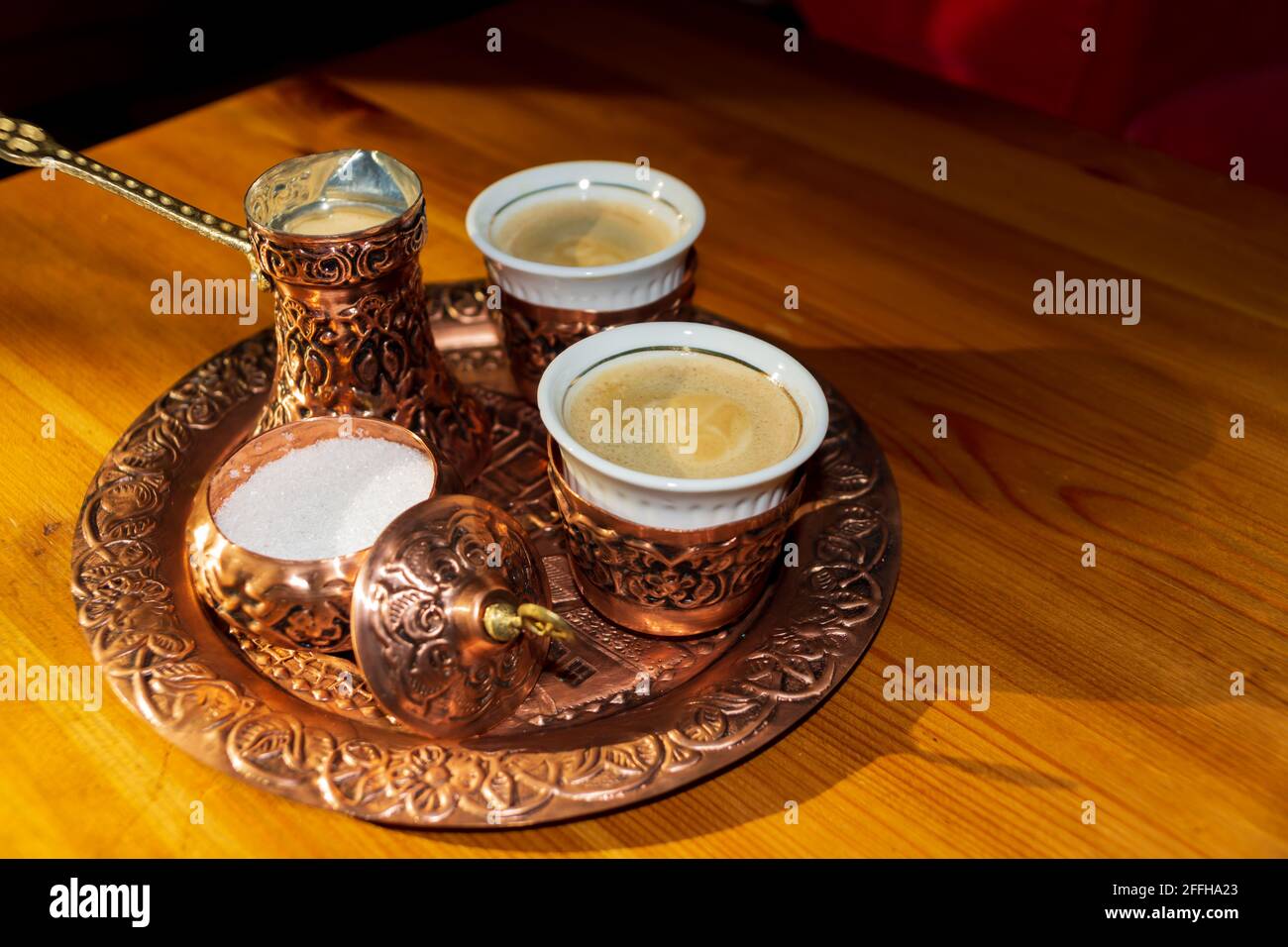 Türkischer Kaffee in Kupferbecher und -Topf serviert.Kaffeebohnen auf braunem Holztisch. Stockfoto