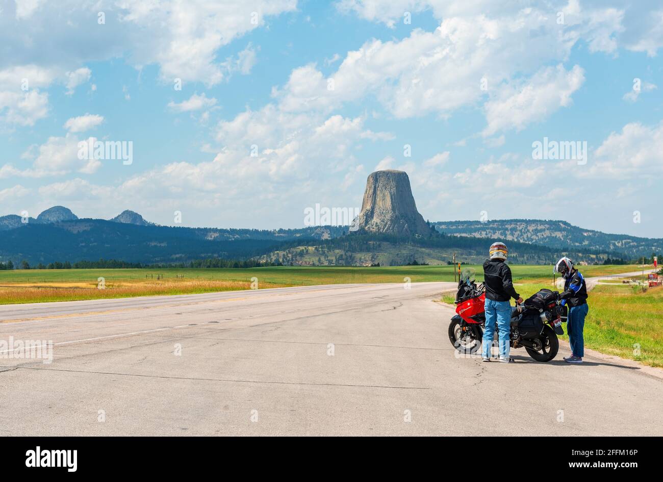 Motorradfahrer mit Motorrad entlang der Autobahn mit Devils Tower Nationaldenkmal, Wyoming, Vereinigte Staaten von Amerika, USA. Stockfoto