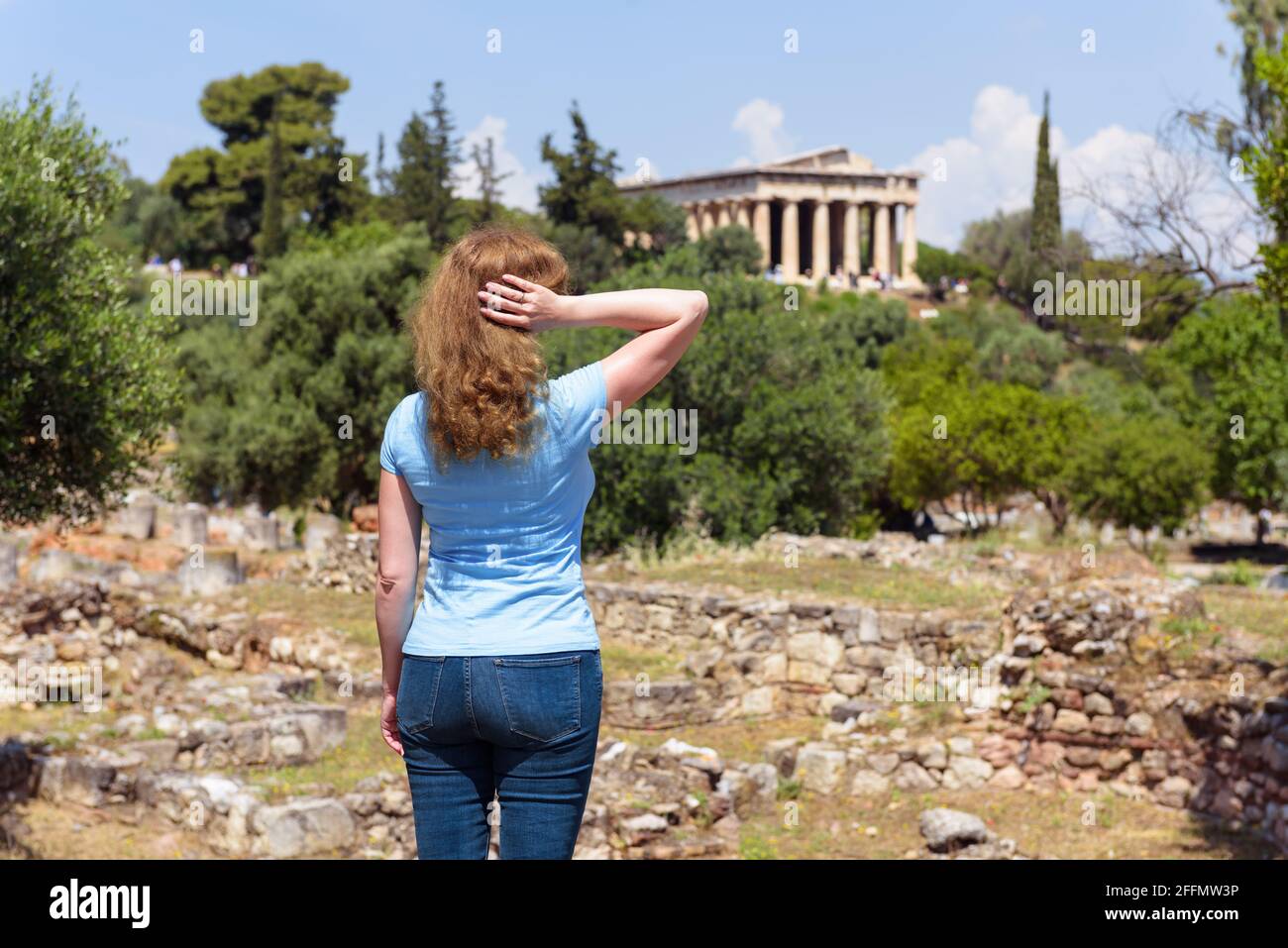 Junge Frau blickt auf den Tempel von Hephaestus, Athen, Griechenland. Diese altgriechische Struktur ist eines der Hauptmerkmale Athens. Touristen besuchen die Agora i. Stockfoto