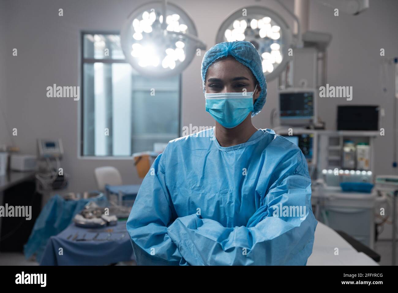 Mixed Race weibliche Chirurgen mit Gesichtsmaske trägt Schutzkleidung Im Operationssaal Stockfoto