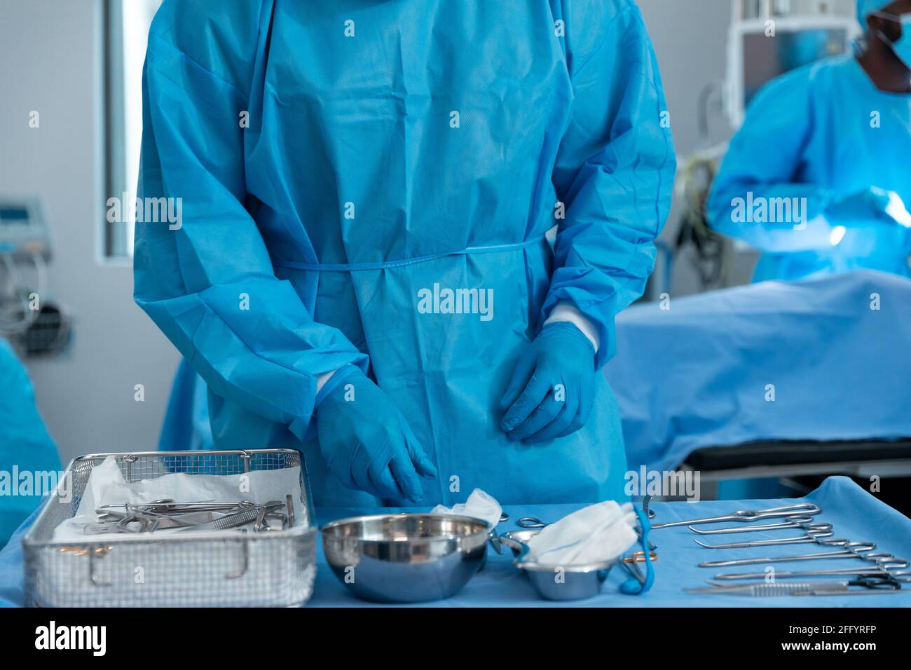 Mittelteil eines männlichen Chirurgen, der im Operationssaal Schutzkleidung trägt Stockfoto