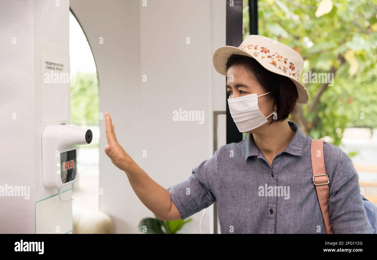 Weibliche Touristen benutzen das Infrarot-Thermometer, bevor sie das Restaurant betreten Stockfoto