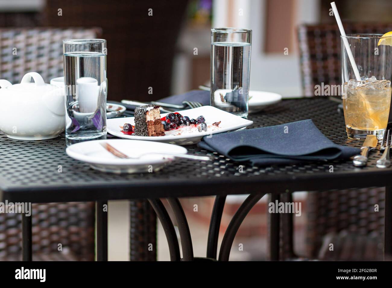 Konzept für Speisereste mit einem Café-Tisch im Freien, an dem kein Kunde, sondern übrig gebliebene Kuchen und Getränke, die zertrümmert werden, zu sehen sind. Rücksichtslos Stockfoto
