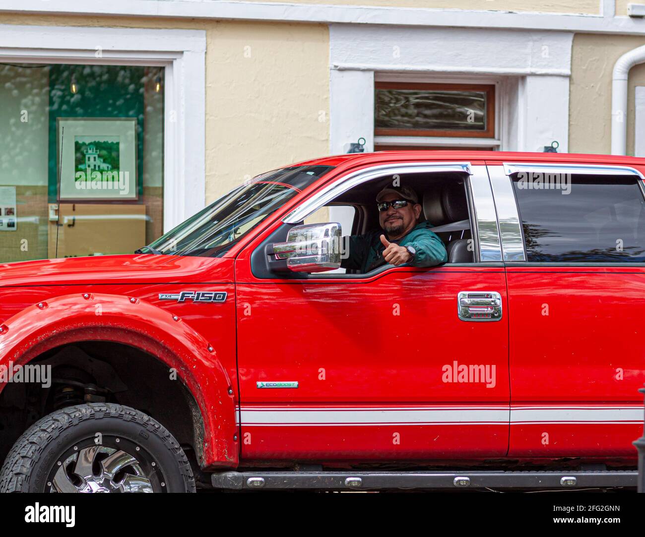04-16-2021 Easton, MD, USA: Ein Mann mit Spitzbart fährt einen ford F-150 Pickup Truck. Er gibt ein Daumen nach oben Zeichen mit seiner Hand durch den Sieg Stockfoto
