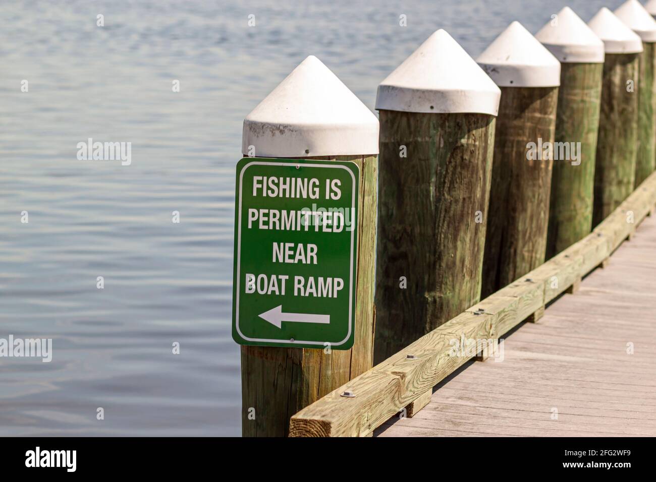 Angeln ist in der Nähe von Bootsrampe Zeichen auf grünen Metallplatte an einem Dock Post an der Küste eines lokalen Hafens angebracht erlaubt. Stockfoto