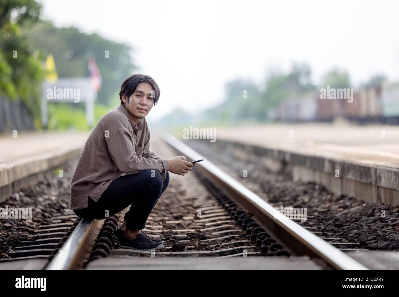 Deprimiert junger Mann sitzt auf Gleis Stockfoto