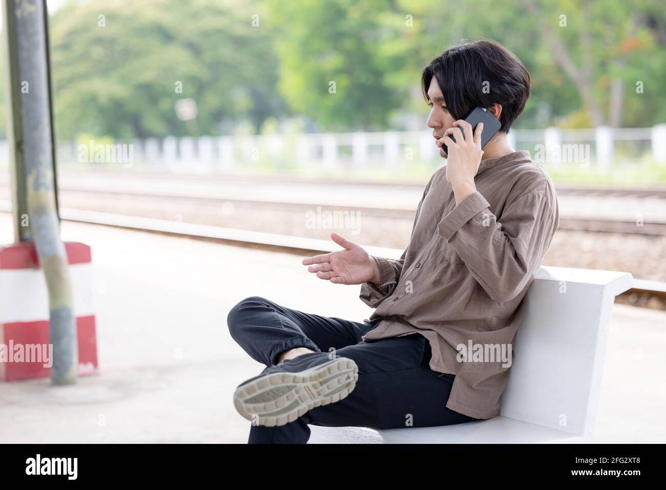 Mann, der bei einem mobilen Anruf in der Nähe des Bahnhofs in Thailand arbeitet Stockfoto