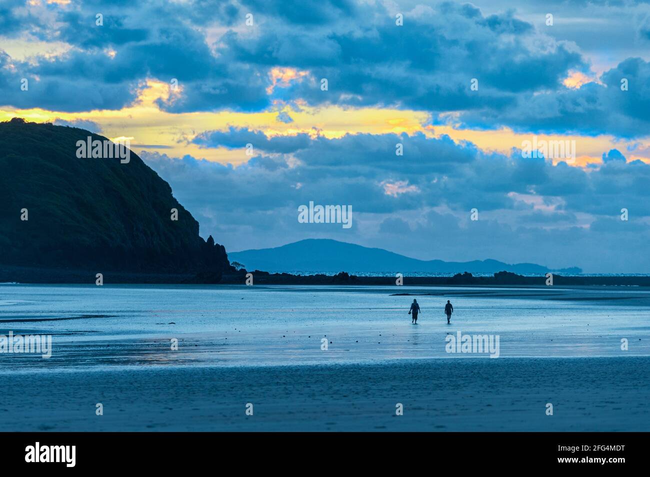 Zwei Personen, die bei Sonnenaufgang am Strand spazieren, Cape Hillsborough, Queensland, QLD, Australien Stockfoto
