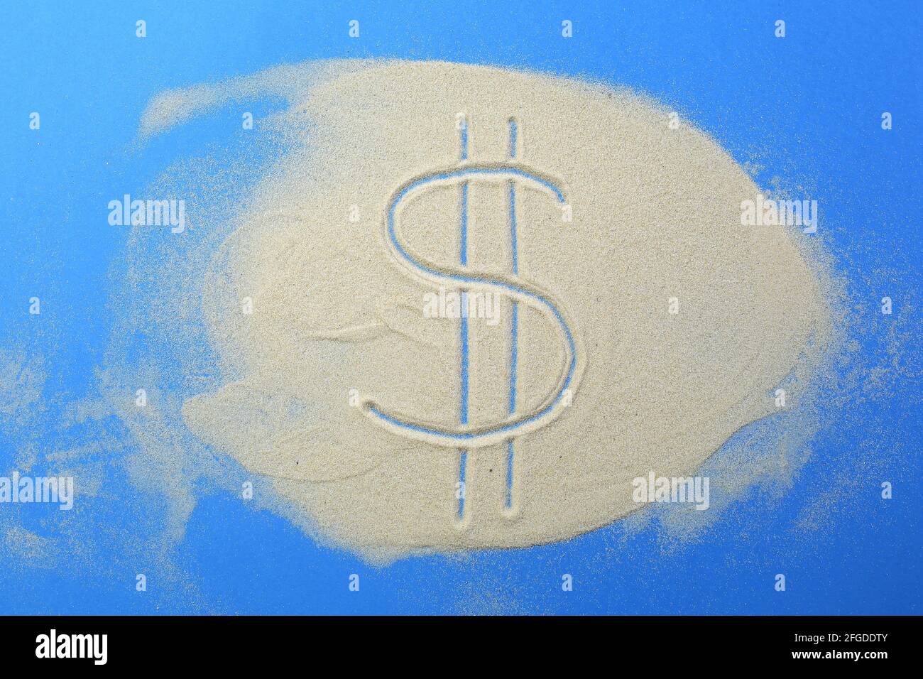 Das Dollarsymbol ist in den Sand auf einem Blau geschrieben Hintergrund Stockfoto