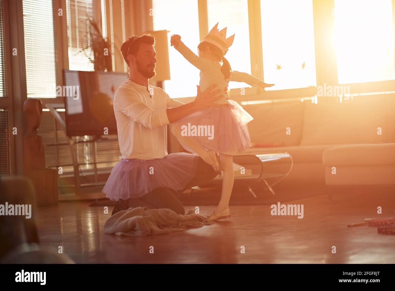 Ein junger Vater liebt es, mit seiner kleinen Tochter in einer schönen Atmosphäre zu Hause an ihren Ballettzügen zu arbeiten. Familie, zusammen, zu Hause Stockfoto
