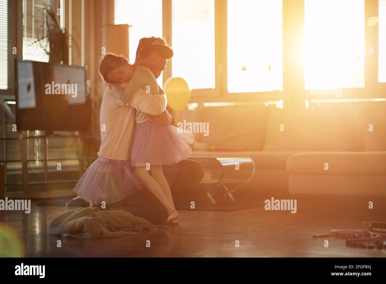 Ein junger Vater und seine kleine Tochter sind voller Emotionen, während sie zu Hause in einer schönen Atmosphäre ein Balletttraining machen. Familie, zusammen, ho Stockfoto