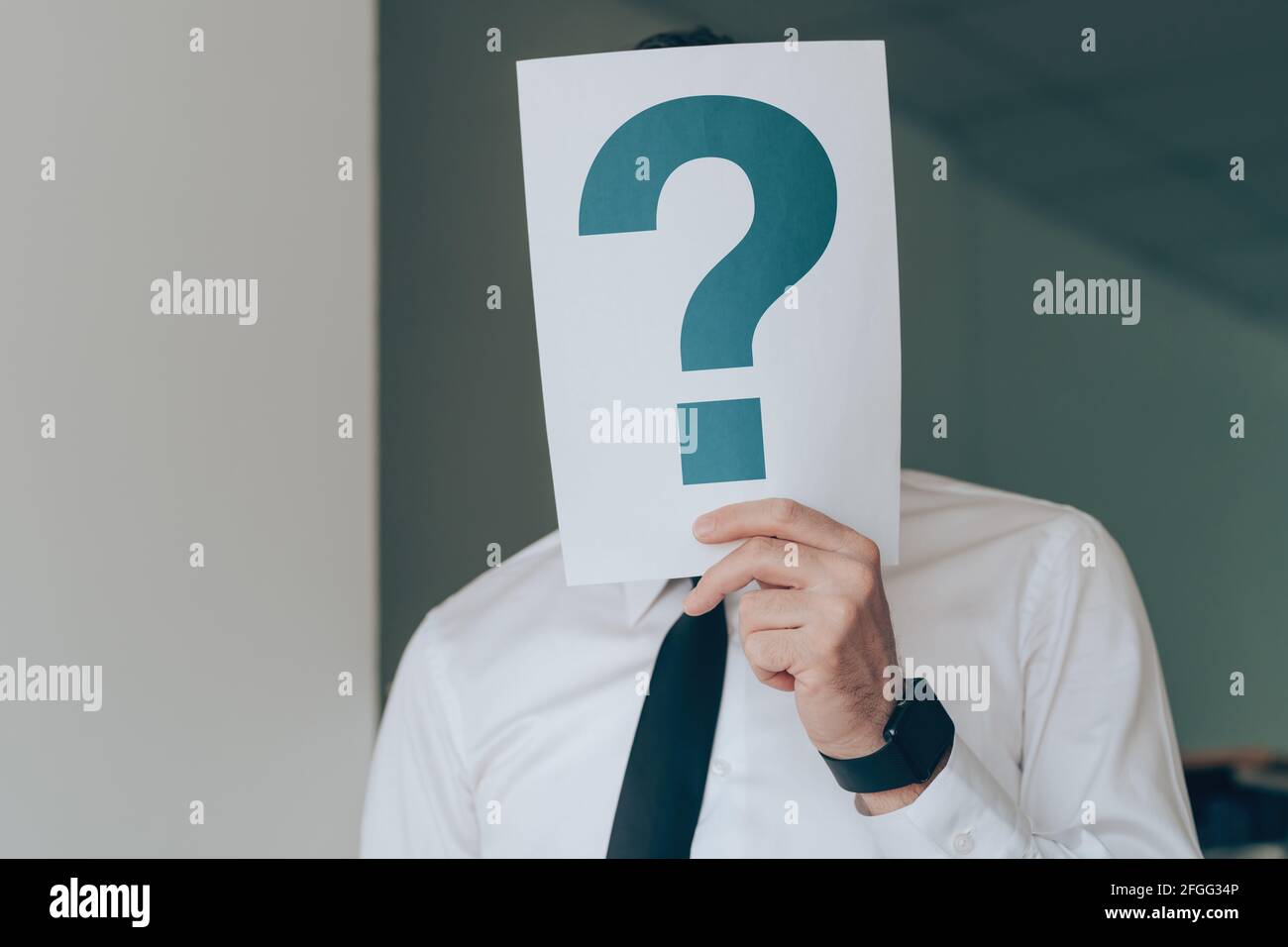 Geschäftsmann hält Papier mit aufgedrucktem Fragezeichen über seinem Gesicht, selektiver Fokus Stockfoto