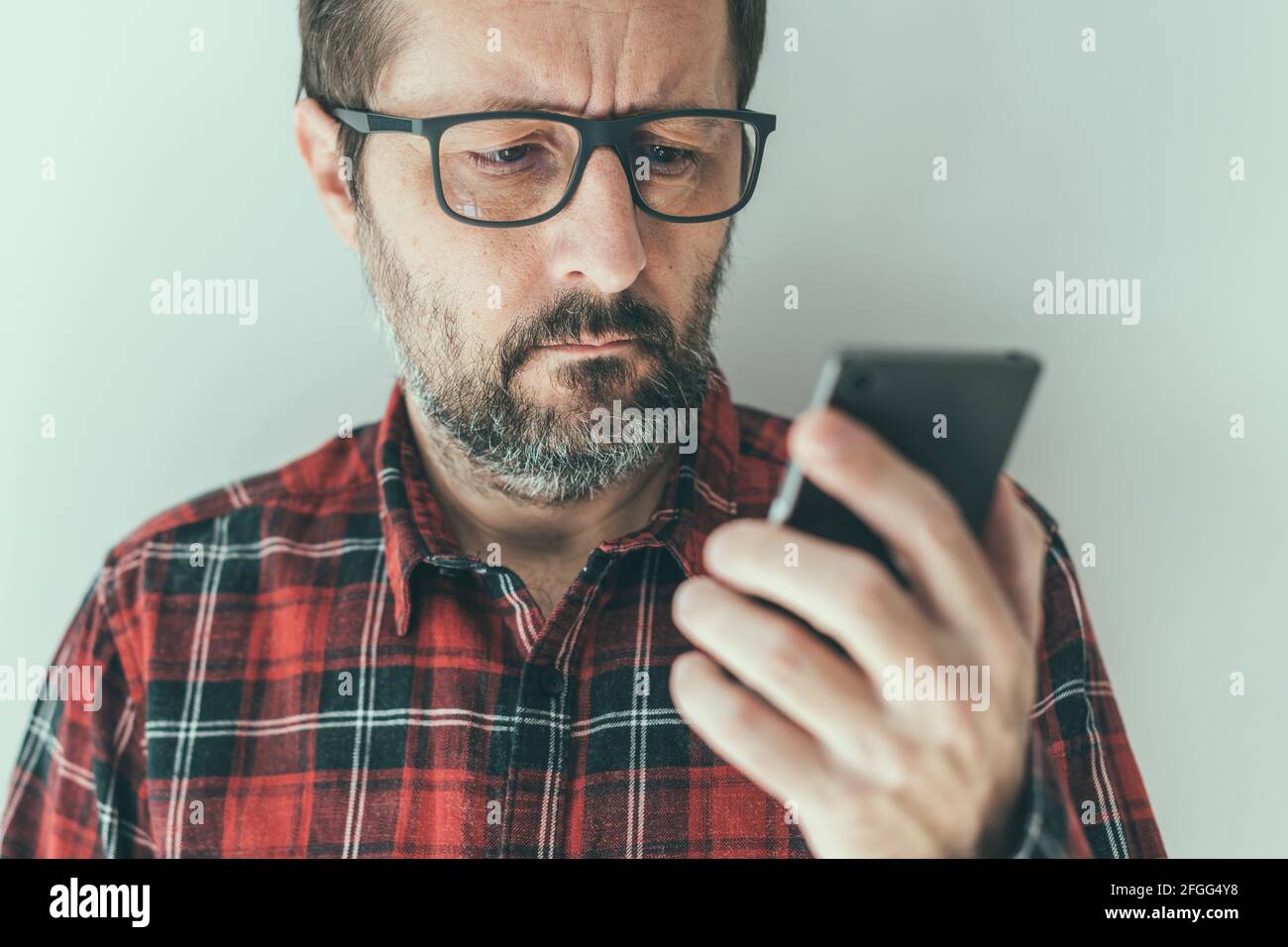 Kopfbild eines Mannes mit mittlerem Erwachsenenalter, der SMS-Benachrichtigungen auf dem Mobiltelefon liest, Nahaufnahme mit selektivem Fokus Stockfoto
