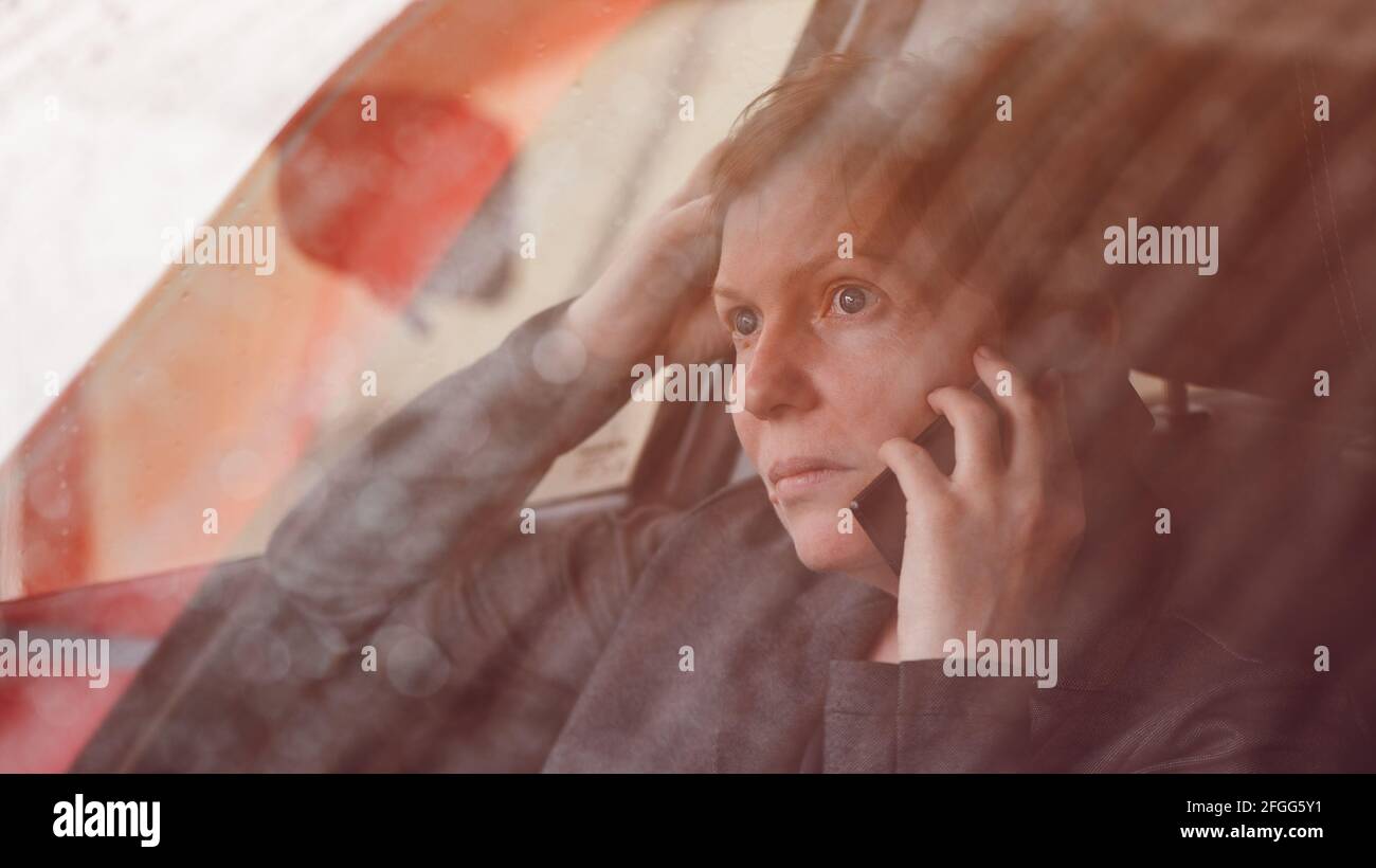 Ernst besorgte Frau, die aus dem Auto auf dem Mobiltelefon spricht, selektiver Fokus Stockfoto