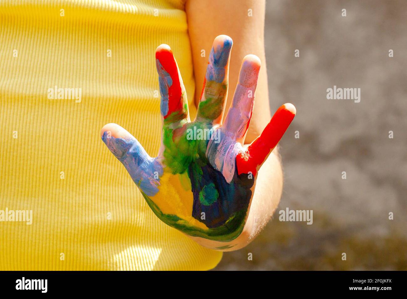 Bunte Kinderhand, Kind zeigt einfarbige Handfläche mit Farbe bedeckt, um die Kamera, Kreativität, Kunst und Handwerk, Kunsttherapie, Spaß Handwerk ein Stockfoto