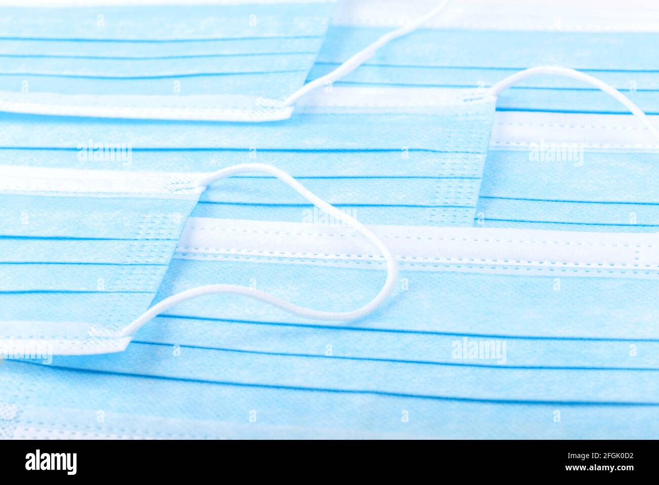 Mehrere einfache blaue schützende medizinische antivirale Gesichtsmasken Set, abstrakte Hintergrundtextur. Viele Gesichtsmasken, die auf einer Ebenen Fläche liegen, kre Stockfoto