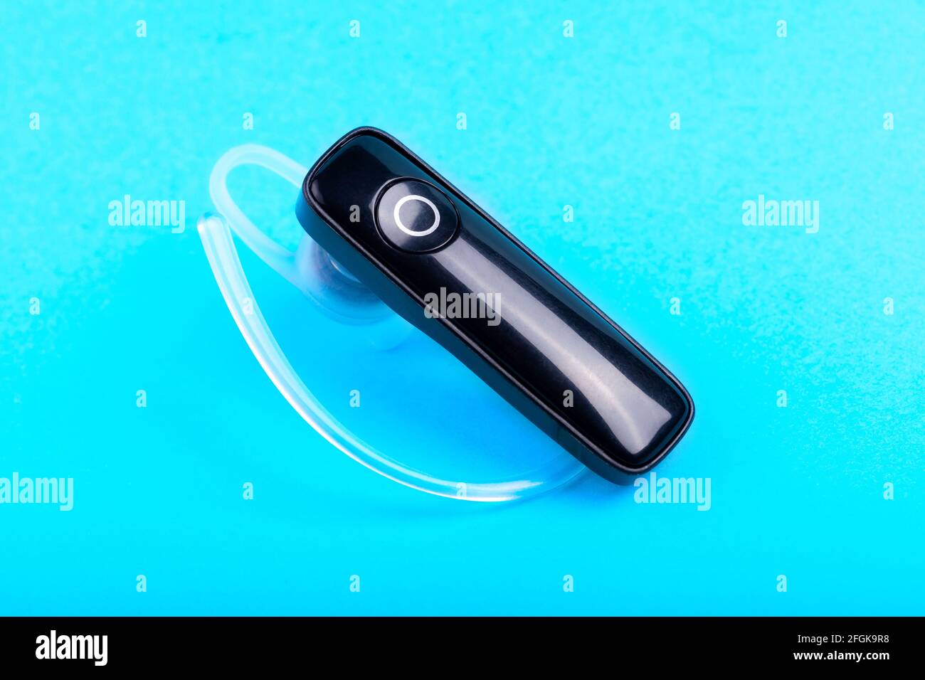Ein ergonomischer kabelloser Ohrhörer, freihändiges Mono-Ohrhörerchen, Zubehör für sichere Freisprechgespräche, ein Ohrhörer auf blauem Hintergrund, Phone Smar Stockfoto