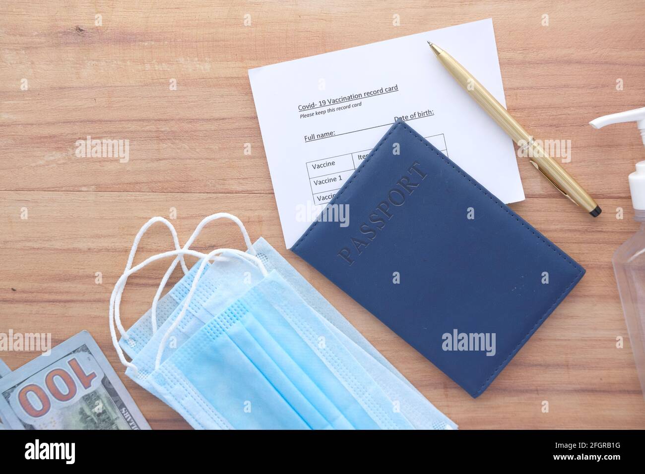 Pass, Impfausweis, Handdesinfektionsmittel und Maske auf dem Tisch Stockfoto