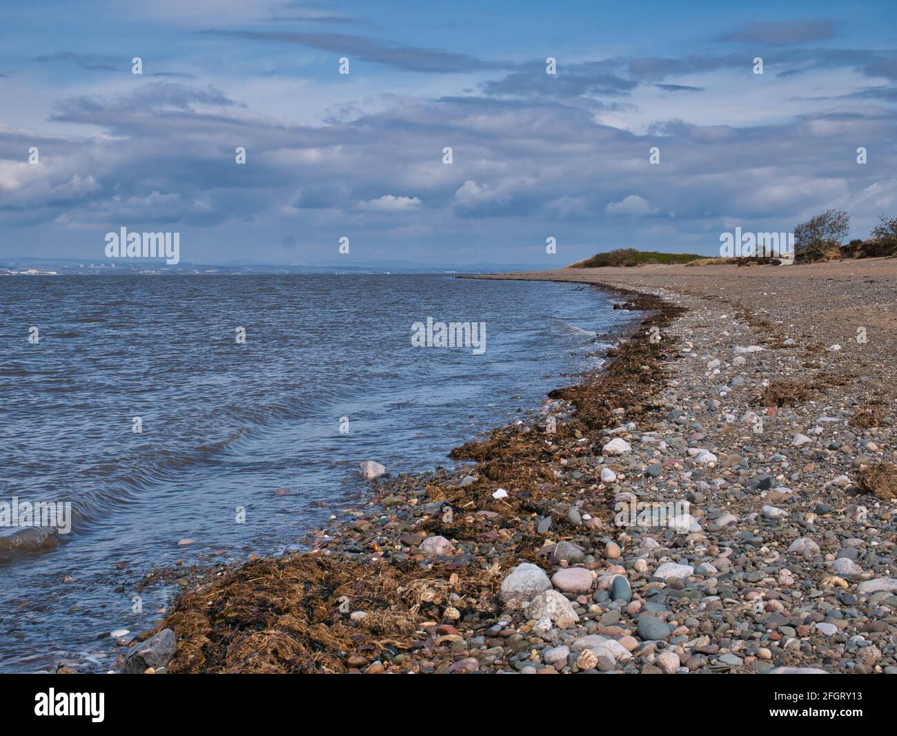 Ein einsamer Kiesstrand zwischen Silloth und Grune Point an der Solway Coast im Nordwesten von Cumbria, England, Großbritannien. Aufgenommen an einem teilweise bewölkten Tag im Frühling Stockfoto