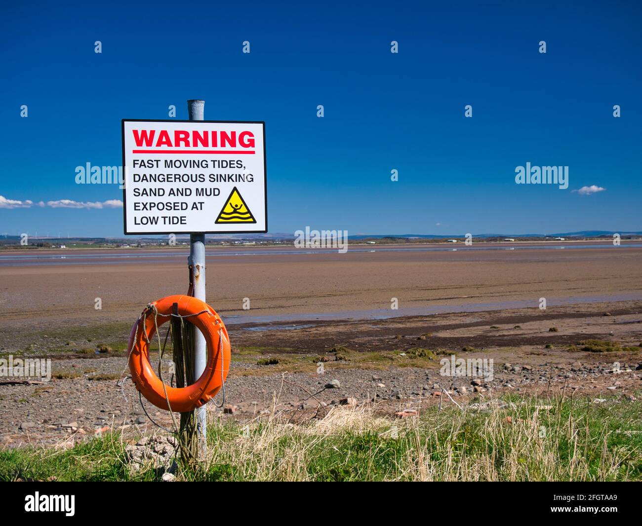 An der nordwestlichen Cumbria Solway Coast warnt ein Schild vor gefährlichen Gezeiten, sinkenden Sand- und Schlammabsenkungen bei Ebbe. Stockfoto