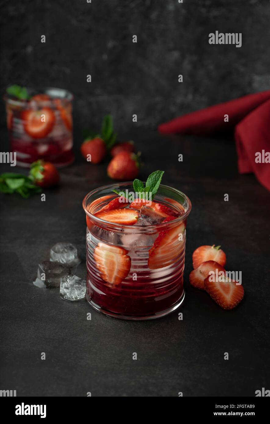 Bar-Magazin-Konzept. Cocktail, Getränk mit Eis und frischen Erdbeeren. Mit Minzblättern. Dezere, dunkle Stimmung Stockfoto