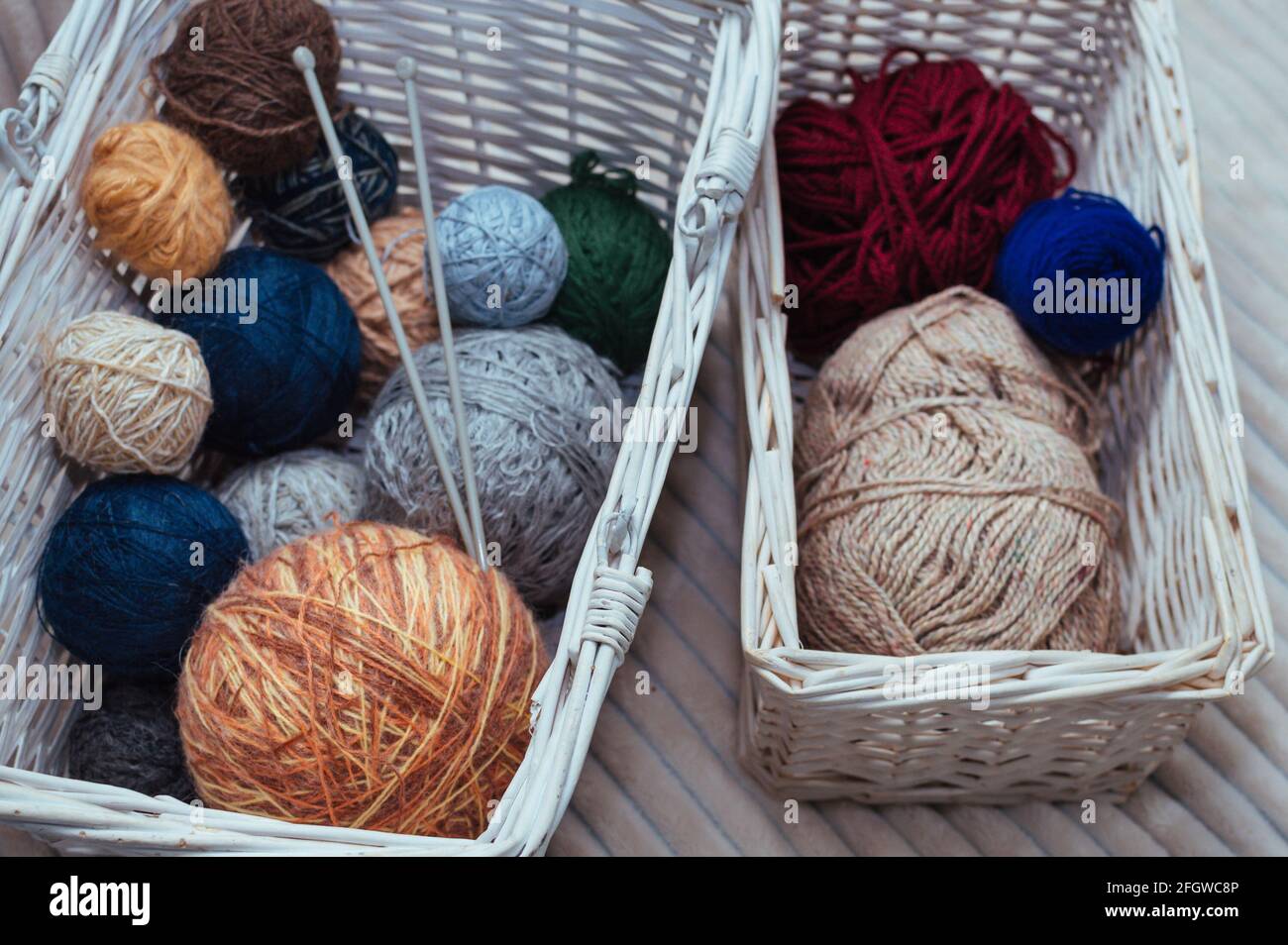 Zwei weiße Körbe mit Garn und Stricknadeln Stockfoto