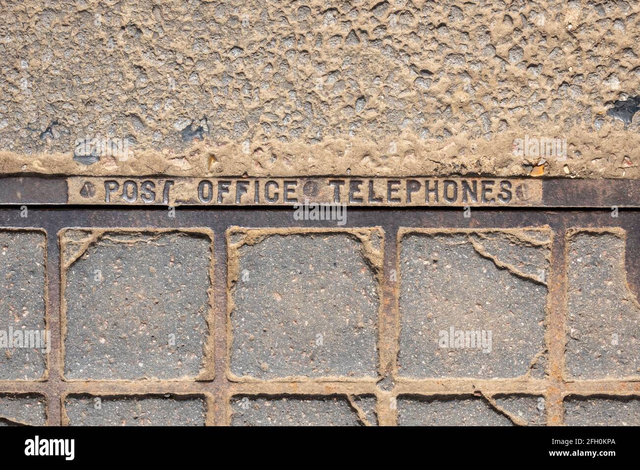 Posttelefone Inspektionsabdeckung aus Gusseisen und Beton Auf der Fahrbahn montiert Stockfoto