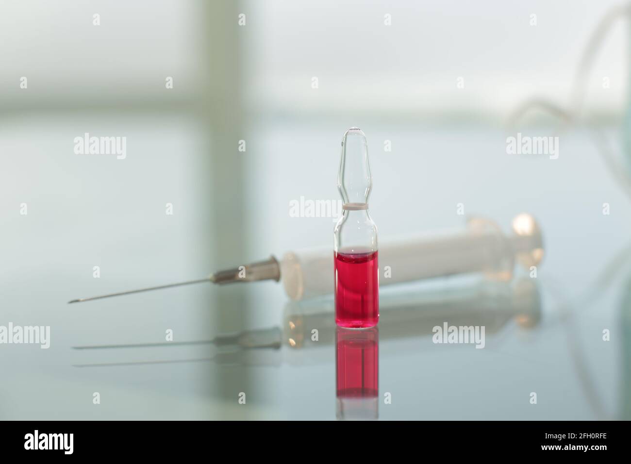 Spritze und Fläschchen mit Impfstoff auf Glastisch Stockfoto