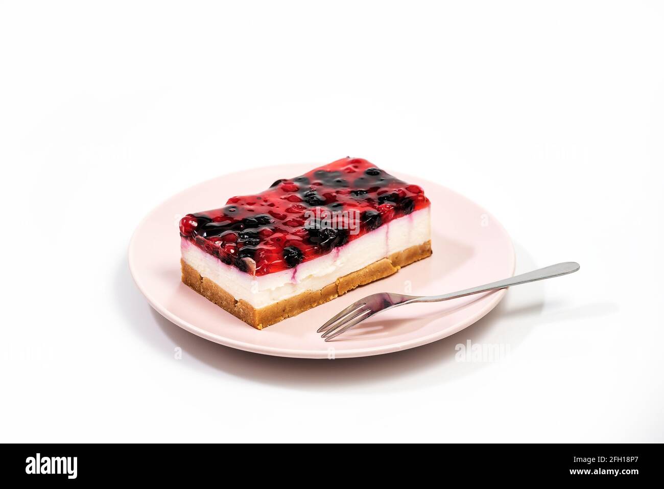 Käsekuchen mit Himbeer- und Johannisbeersoße auf einem rosafarbenen ...
