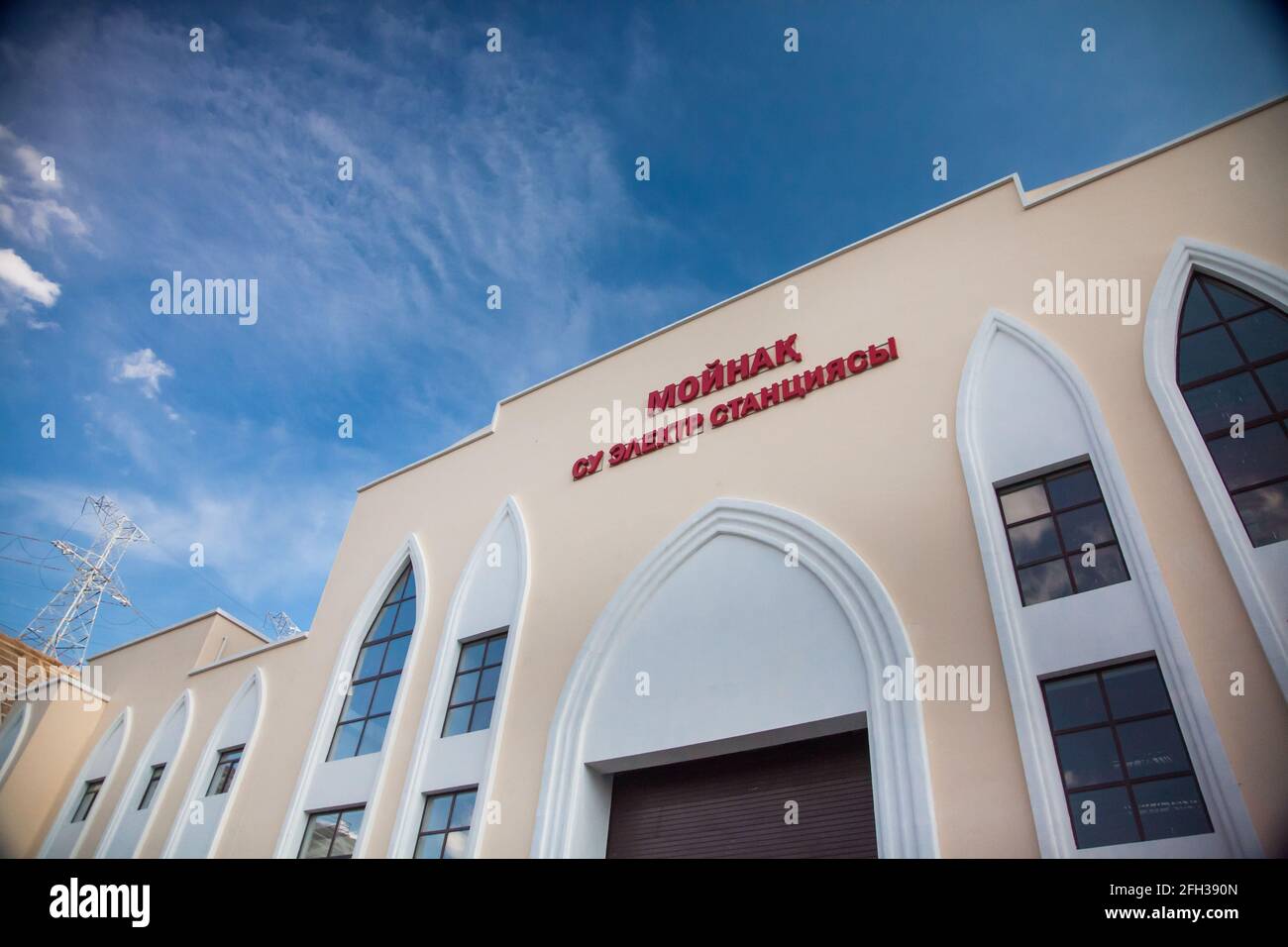 Wasserkraftwerk Moinak, Hauptgebäude. Nahaufnahme des Fotos. Blauer Himmel mit Wolken und elektrischem Mast im Hintergrund. Stockfoto