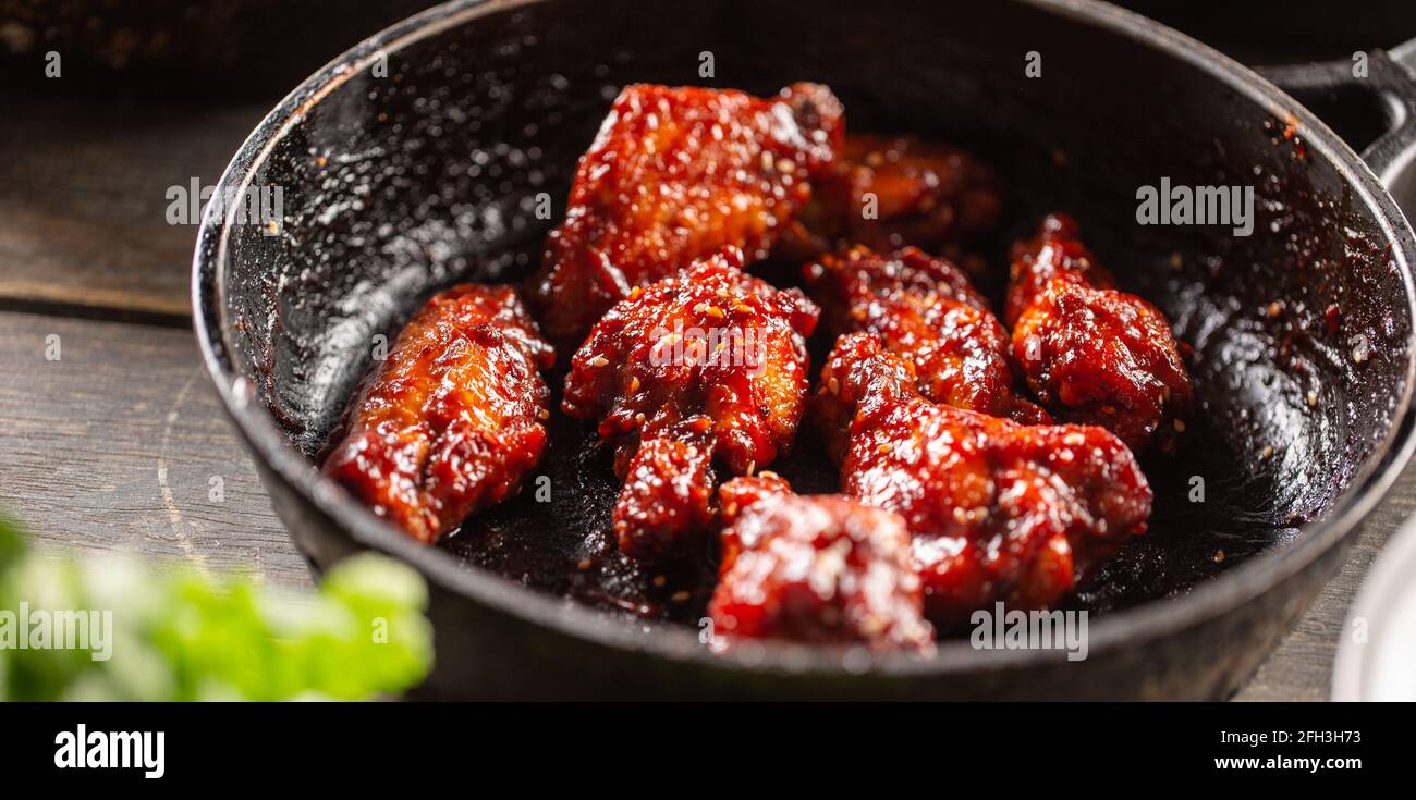 Würzig glasierte marinierte Hähnchenflügel in einer dunklen Pfanne. Stockfoto