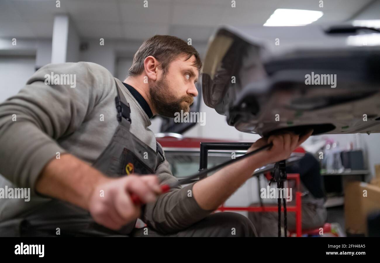 Bärtiger Mitarbeiter im Reparaturdienst, reicht im Arbeitsprozess ein Foto aus Stockfoto