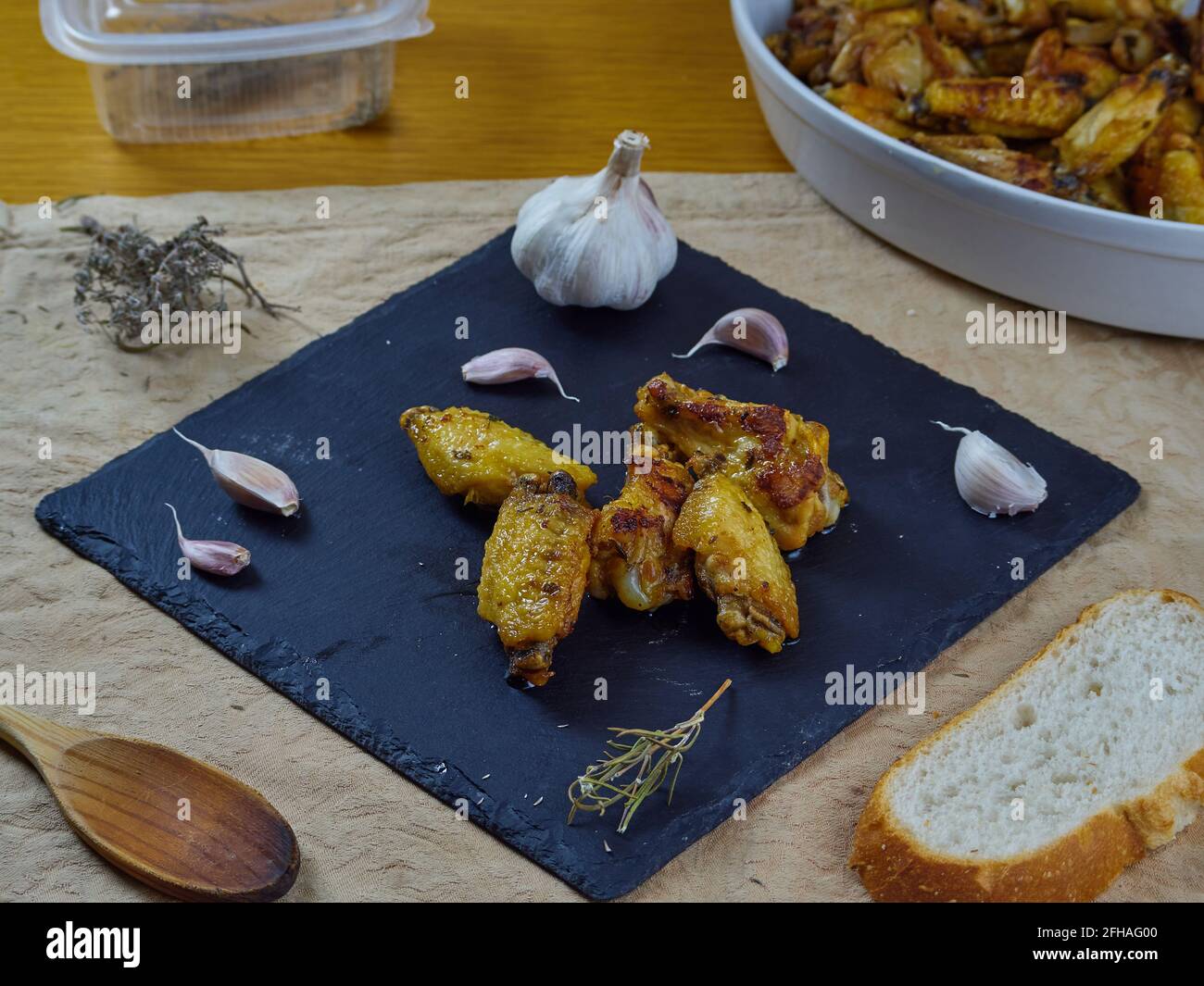 Knoblauch-Hühnerflügel (Pollo al ajillo). Spanisches Tapas-Gericht, serviert mit knusprigem Brot, einer Platte und seinen Zutaten auf einer braunen Serviette. Draufsicht Stockfoto